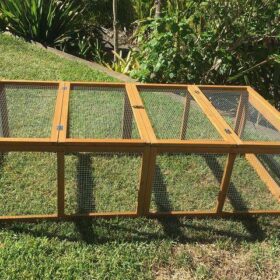 A brown timber guinea pig run sitting on grass.