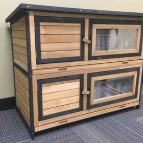 A two storey timber indoor rabbit hutch on carpet.